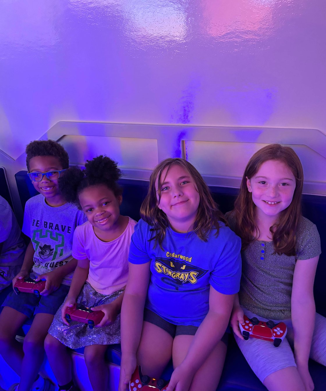 Four smiling kids holding controllers in gaming trailer