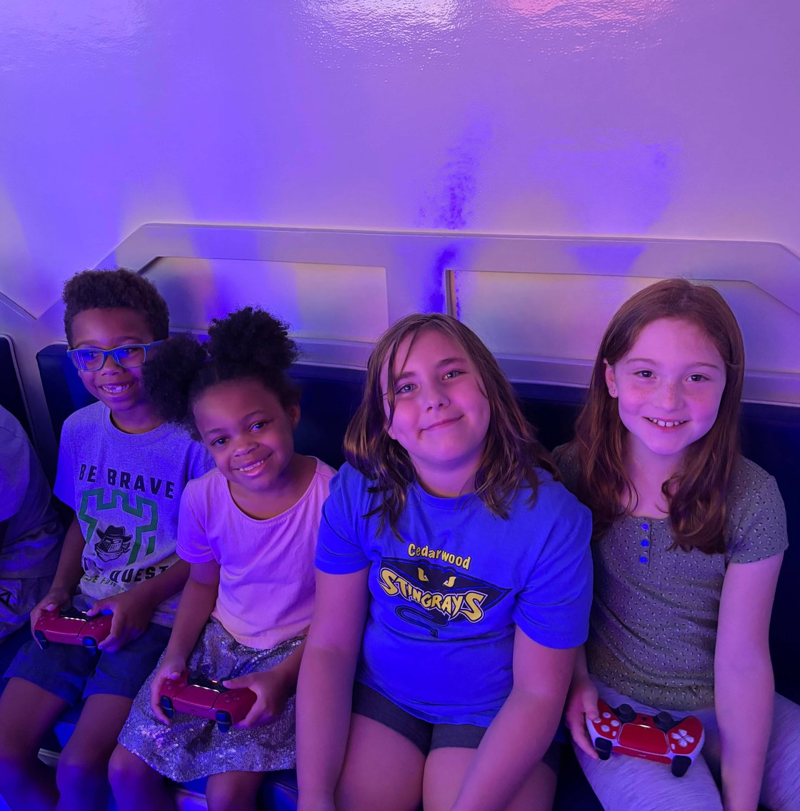Four smiling kids holding controllers in gaming trailer