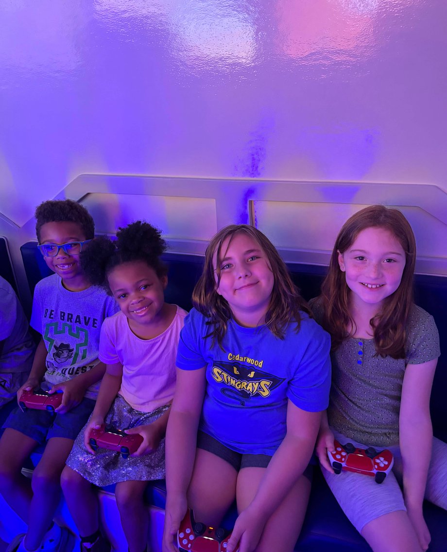 Four smiling kids holding controllers in gaming trailer
