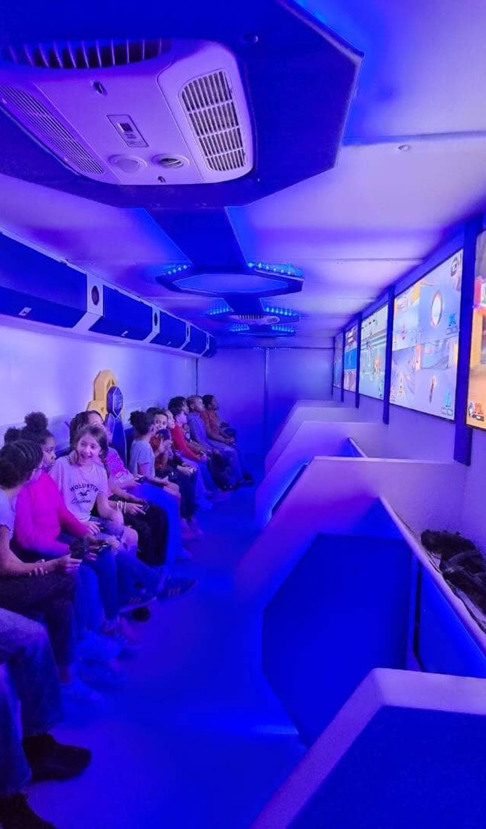 Group of kids gaming on large trailer screens