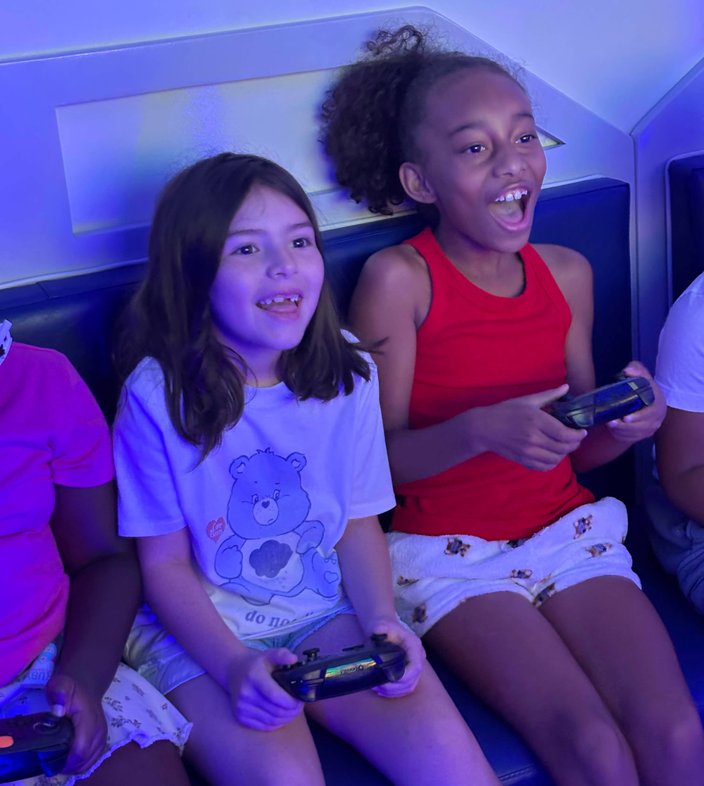 Two girls laughing together holding video game controllers