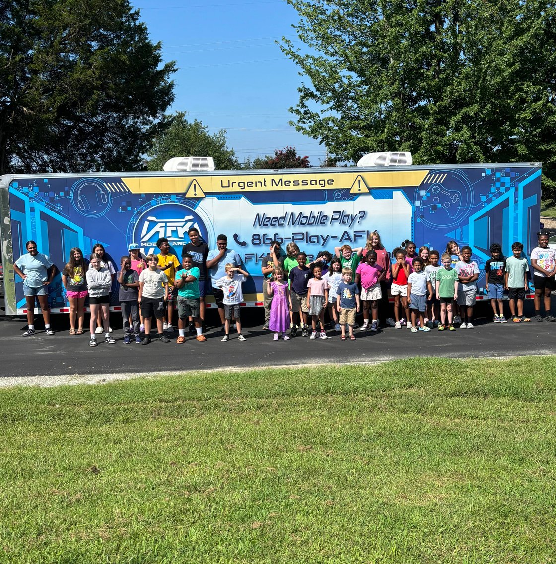 Large group of children posing before gaming trailer